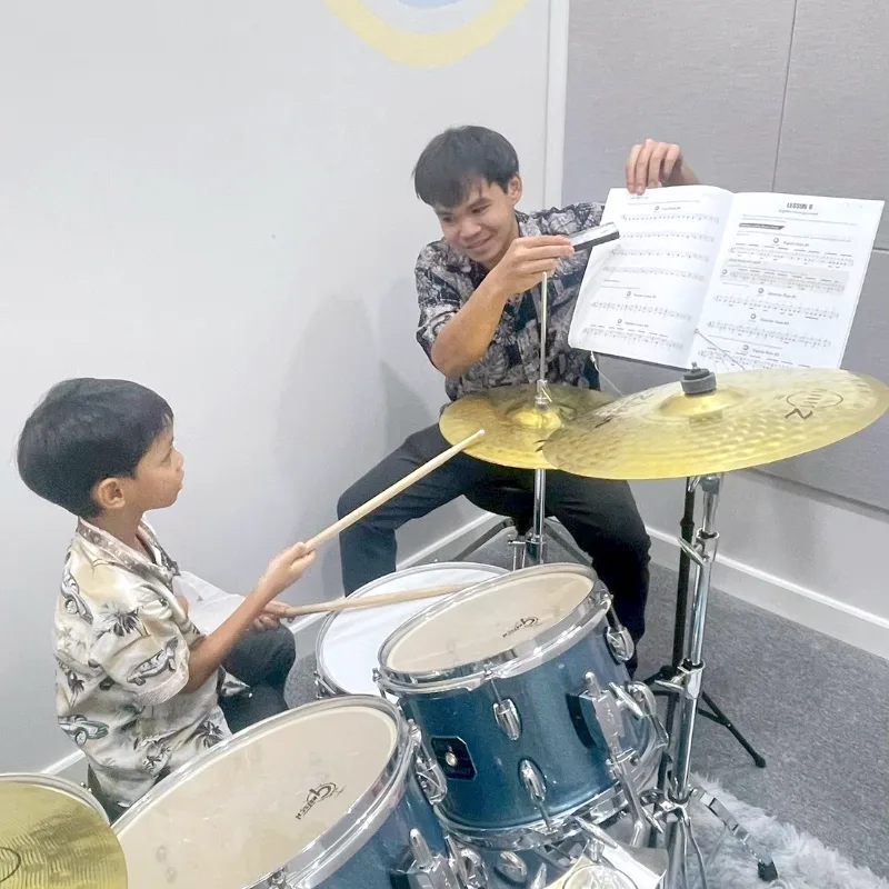 ครูสอนกลองชุดให้นักเรียนเด็กเล็กที่ Music Mastery